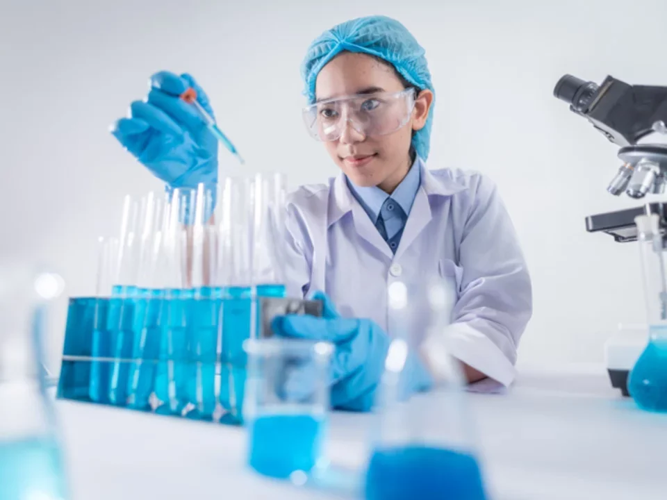 A scientist conducting a test tube experiment with blue liquids and medical droppers  