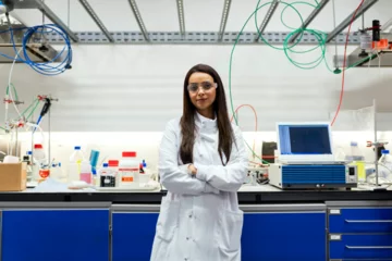 A female trainee in a lab with arms folded. 